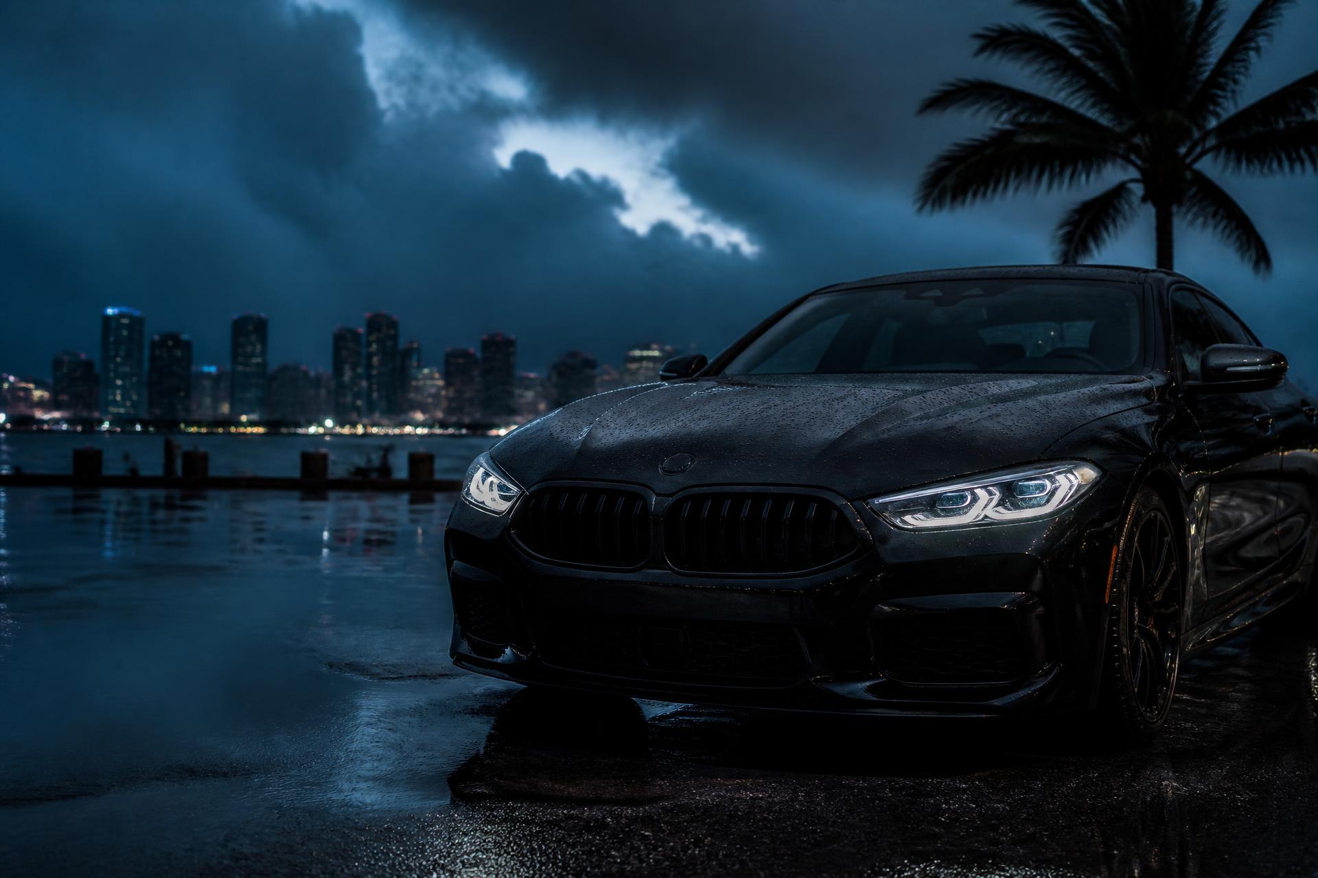 Freshly detailed black sedan gleaming on wet pavement with the Miami skyline behind it